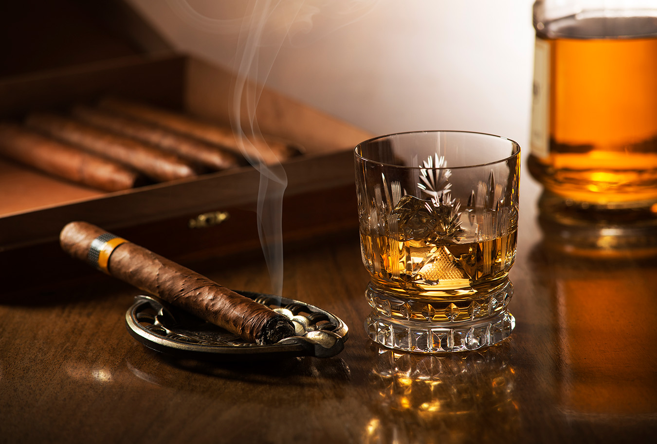 Closeup of cigar and bourbon on wooden table