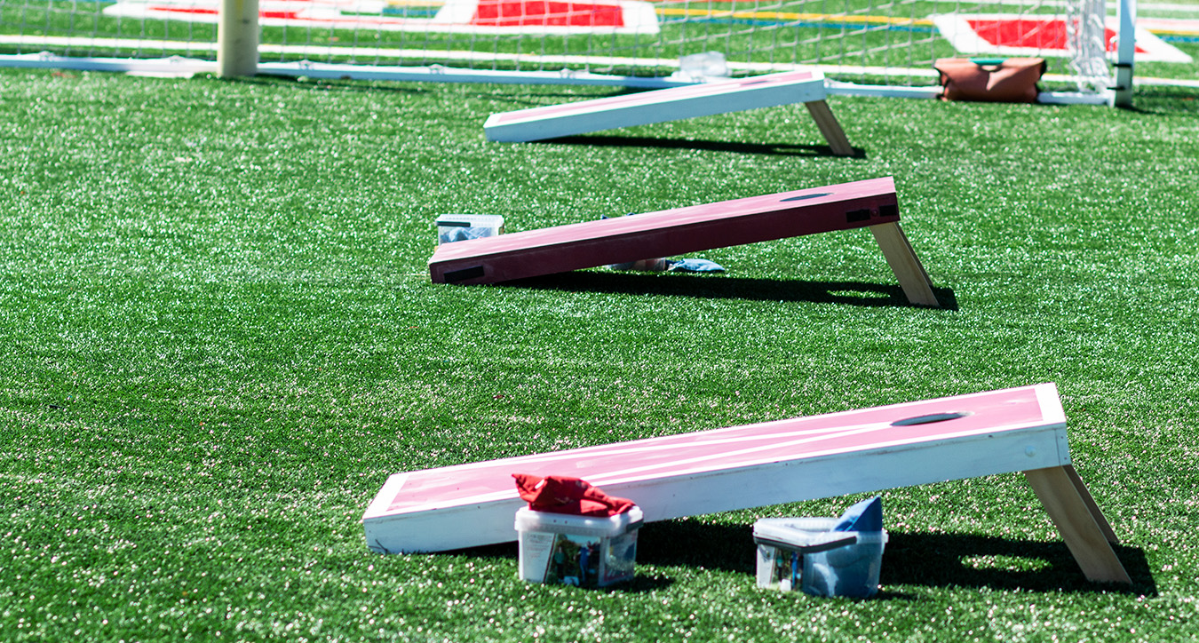 Line of cornhole boards with bean bags on grass