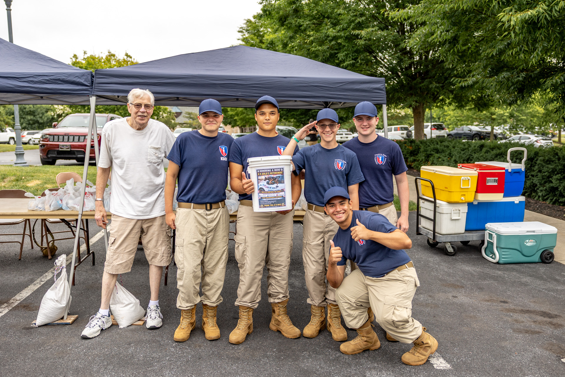 1W8A8961 Man in a white shirt standing with smiling group of boys outdoors.